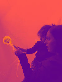 Mother and daughter looking at illuminated jellyfish in aquarium