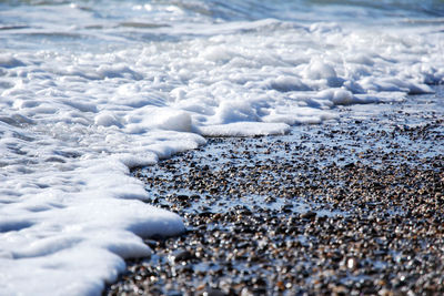 Sea foam wave and wet pebbles on the beach