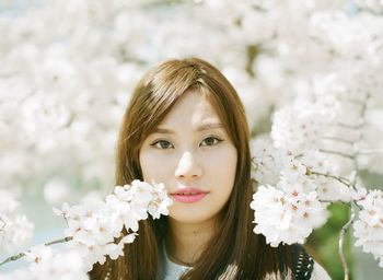 Close-up portrait of a young woman against flowers