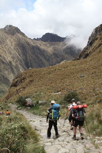 Rear view of hikers on footpath leading towards mountains