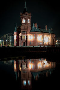 Illuminated church reflecting on lake against sky at night