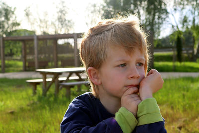 A  boy with sad eyes looks into the distance. a pensive five-year-old boy in the rays of the sun.
