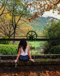 Full length of woman sitting against trees