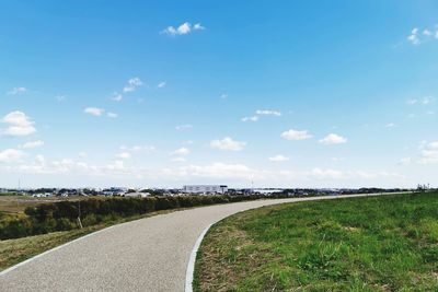 Road amidst field against sky