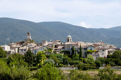 Plants and buildings by mountains against sky