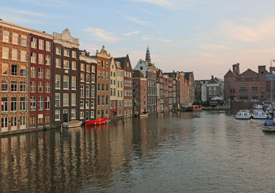 Buildings by canal against sky in city