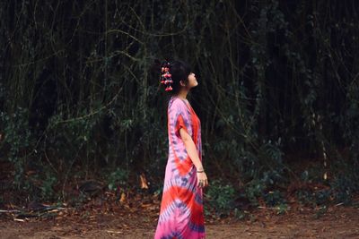 Side view of woman standing in forest