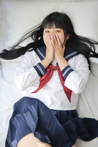 Portrait of young woman sitting on bed at home