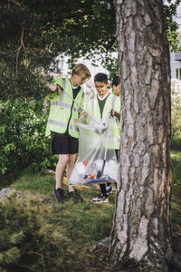 Full length of boys collecting garbage in plastic bag