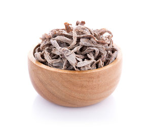 Close-up of dry papaya in bowl against white background