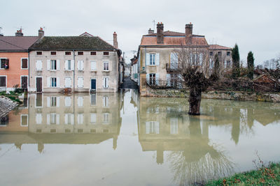 Reflection of house in lake against sky