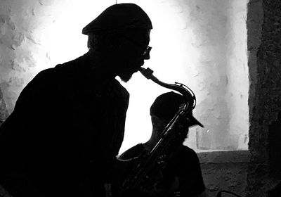 Silhouette man playing guitar against wall