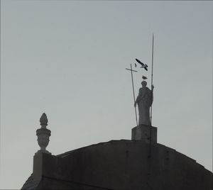 Low angle view of statue against building against clear sky