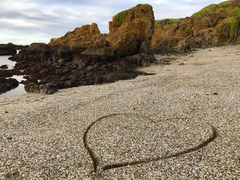 Rock formations on beach against sky