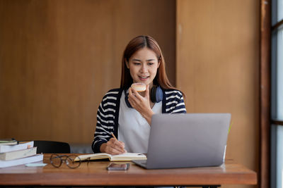 Businesswoman using laptop while sitting on table