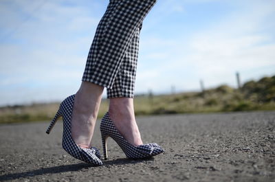 Low section of woman in checked pattern high heels and cloth on road