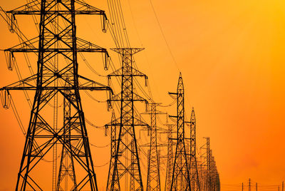 Low angle view of silhouette electricity pylon against sky during sunset