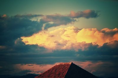 Low angle view of house roof against sky during sunset