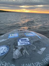 Information sign on beach against sky during sunset