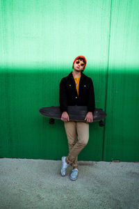 Full length of young man sitting against wall