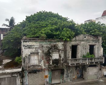 Abandoned building by trees against sky