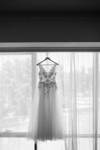 Wedding gown hanging by curtain on wall