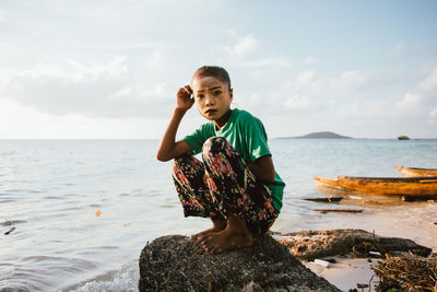 Full length of man on rock at beach against sky