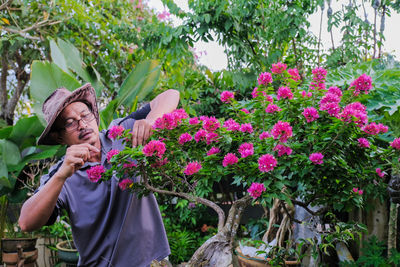 Woman standing by pink flowering plants