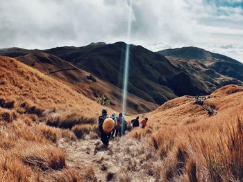 Rear view of people walking on mountain against sky