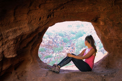 Side view of woman sitting on rock