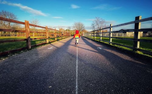 Rear view of woman walking on road against sky