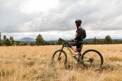 Female mountain biker resting on meadow trail