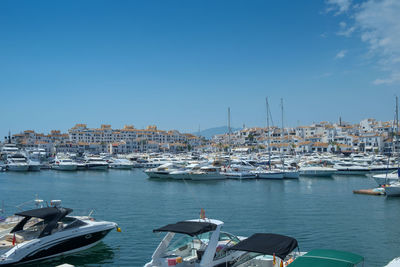 Sailboats moored at harbor against clear blue sky