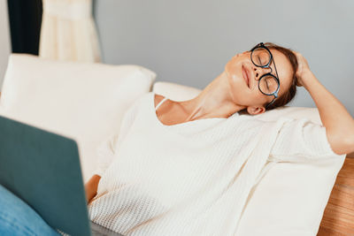 Portrait of woman wearing sunglasses while lying on sofa at home