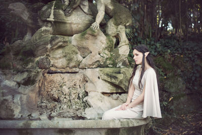 Fairy elf young woman sitting by fountain