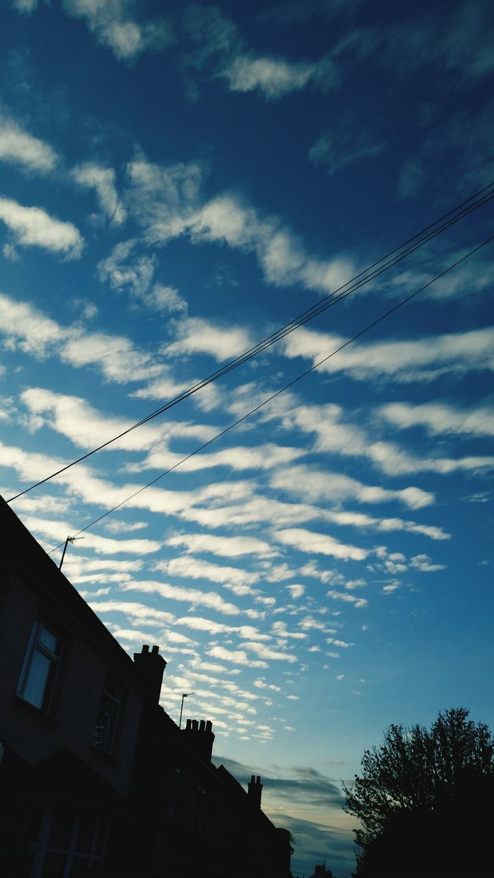 low angle view, sky, architecture, built structure, building exterior, cloud - sky, blue, tree, vapor trail, power line, cloud, outdoors, silhouette, high section, cable, no people, cloudy, street light, building, nature