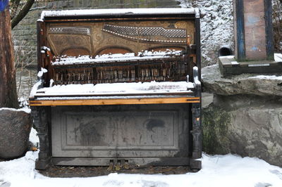Snow covered old building on field during winter