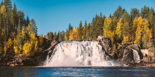 Scenic view of waterfall in forest against sky