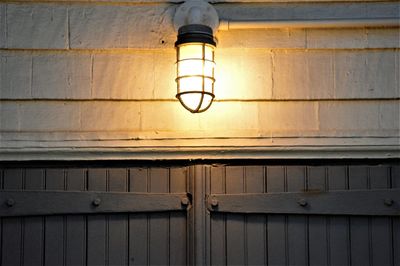 Low angle view of illuminated light bulb hanging on wall