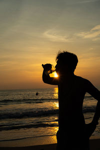 Silhouette man on beach against sky during sunset