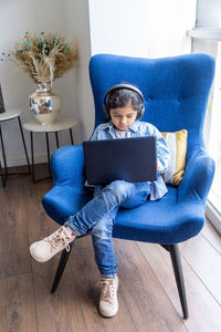 High angle view of girl using laptop while sitting on chair