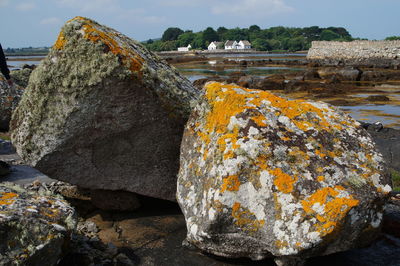 Rock formation by river against sky