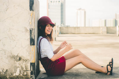 Full length of woman sitting against wall