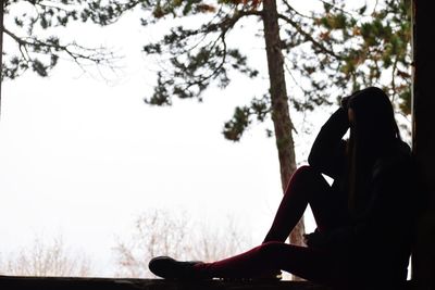 Side view of woman sitting against clear sky