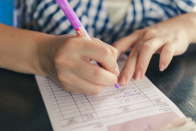 Midsection of woman writing on book