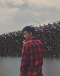 Young man looking away against sky