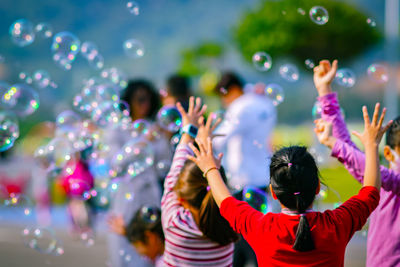 Rear view of girl enjoying bubbles outdoors