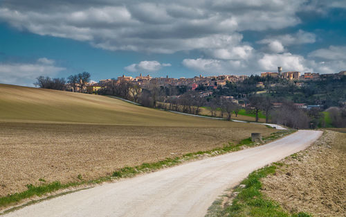 Road amidst field against sky