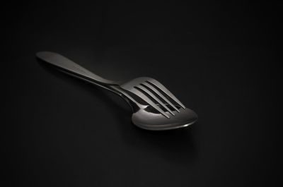 Close up of spoon with fork on black background