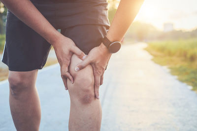 Midsection of man with knee pain standing on road